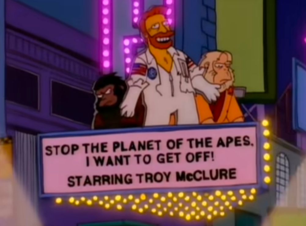 A Broadway marquee says the words "Stop the planet of the apes I want to get off! Starting Troy McClure