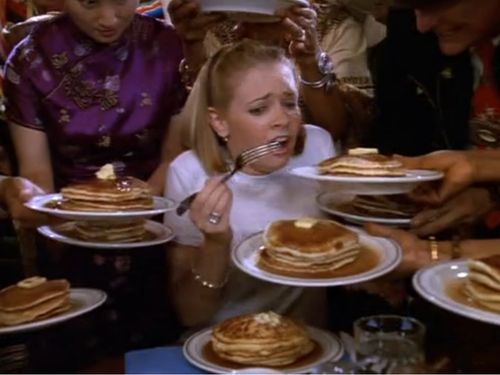 Sabrina's the witch, with lots of people around her giving her pancakes