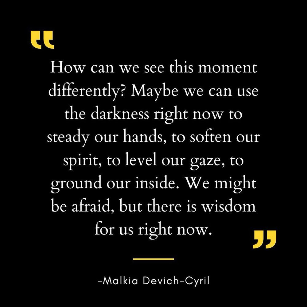 Black background with white text framed by yellow quotation marks at the top and a yellow horizontal line beneath the quote. The quote reads: “How can we see this moment differently? Maybe we can use the darkness right now to steady our hands, to soften our spirit, to level our gaze, to ground our inside. We might be afraid, but there is wisdom for us right now.” Below the yellow line is the attribution: “- Malkia Devich-Cyril.”