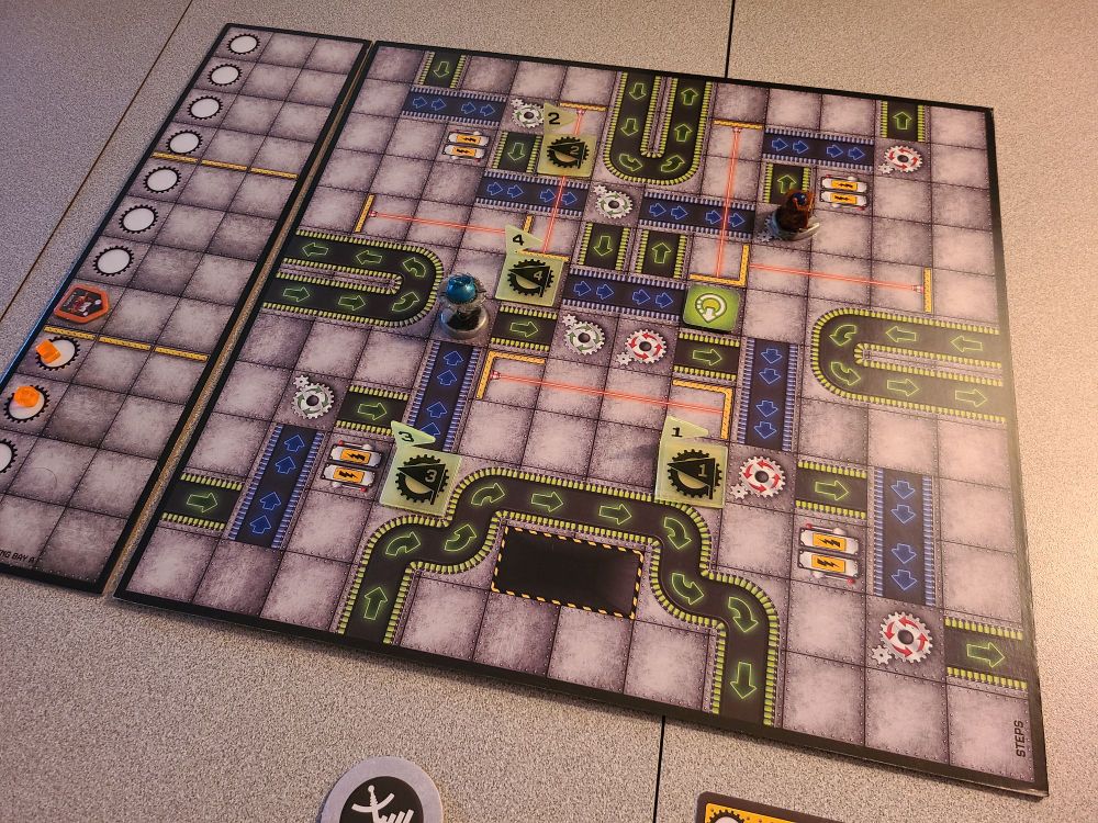 A board for a game of RoboRally, with several features (conveyor belts, rotating gears, etc.) that alter the movement of the two robots on the board.