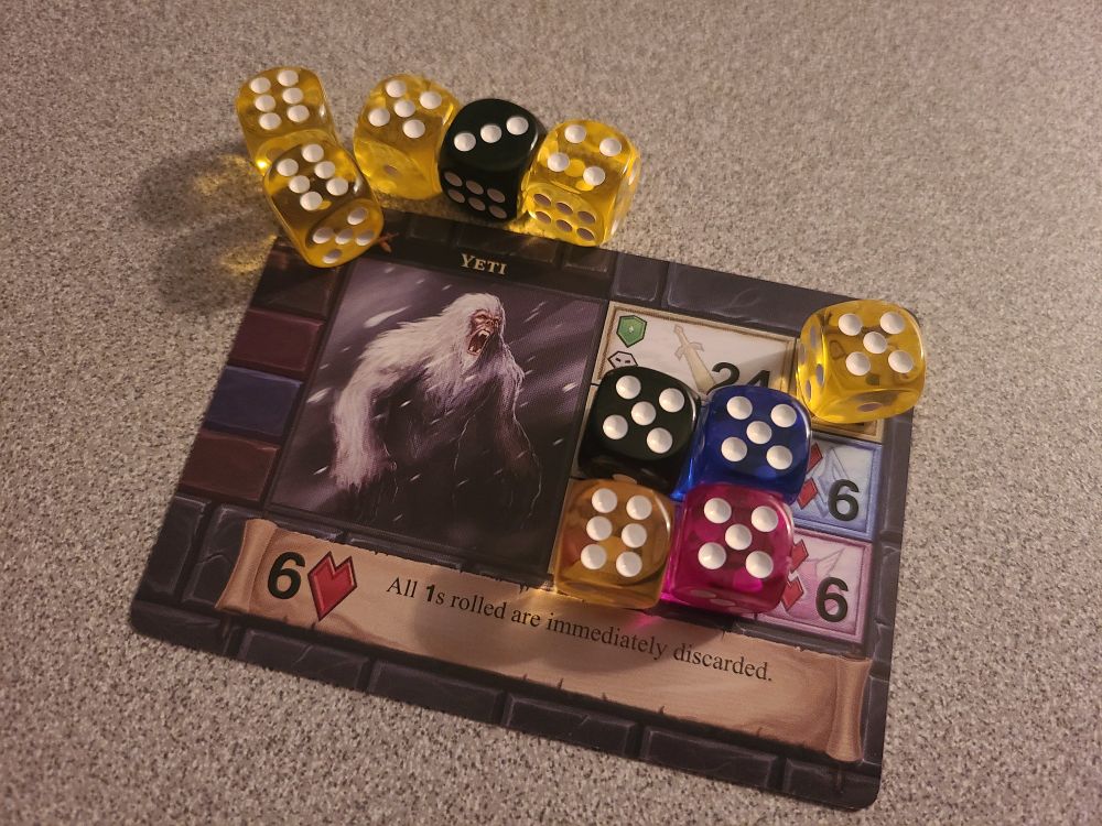The Yeti boss card from One Deck Dungeon, with several coloured dice covering areas of the card to defend against/do damage to it.