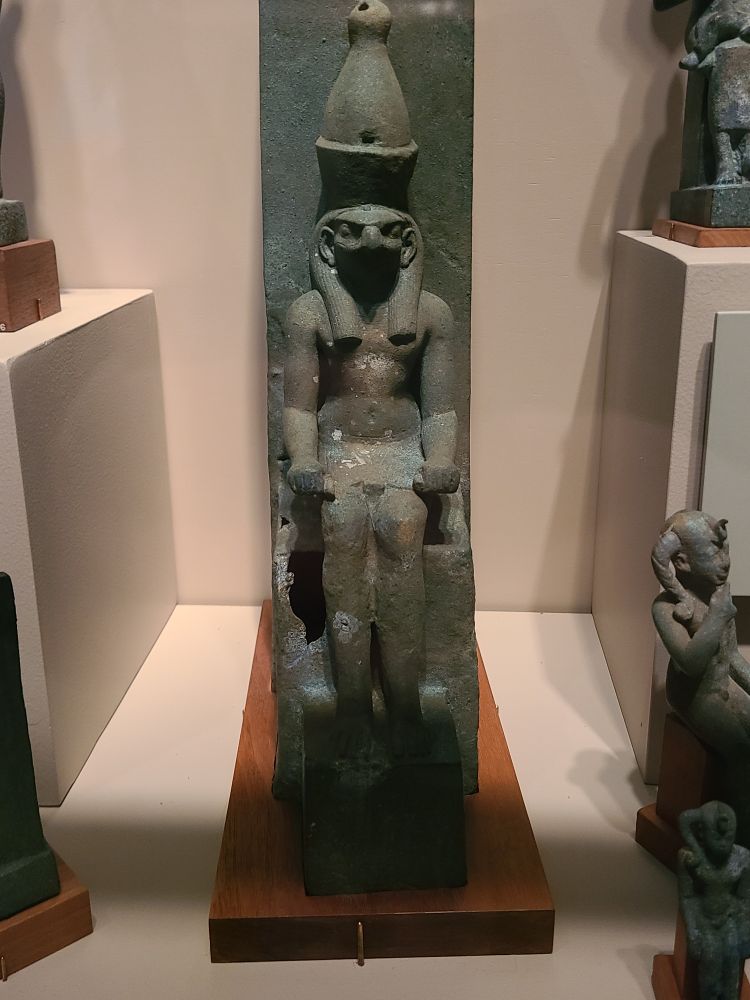 Horus at last becomes partially a man, and is now sitting on a throne. Still silly hat in tow. Bronze statue.