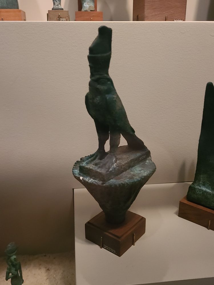Actual ancient Egyptian bird sculpture, of Horus in full falcon mode with a silly lil lotus hat 