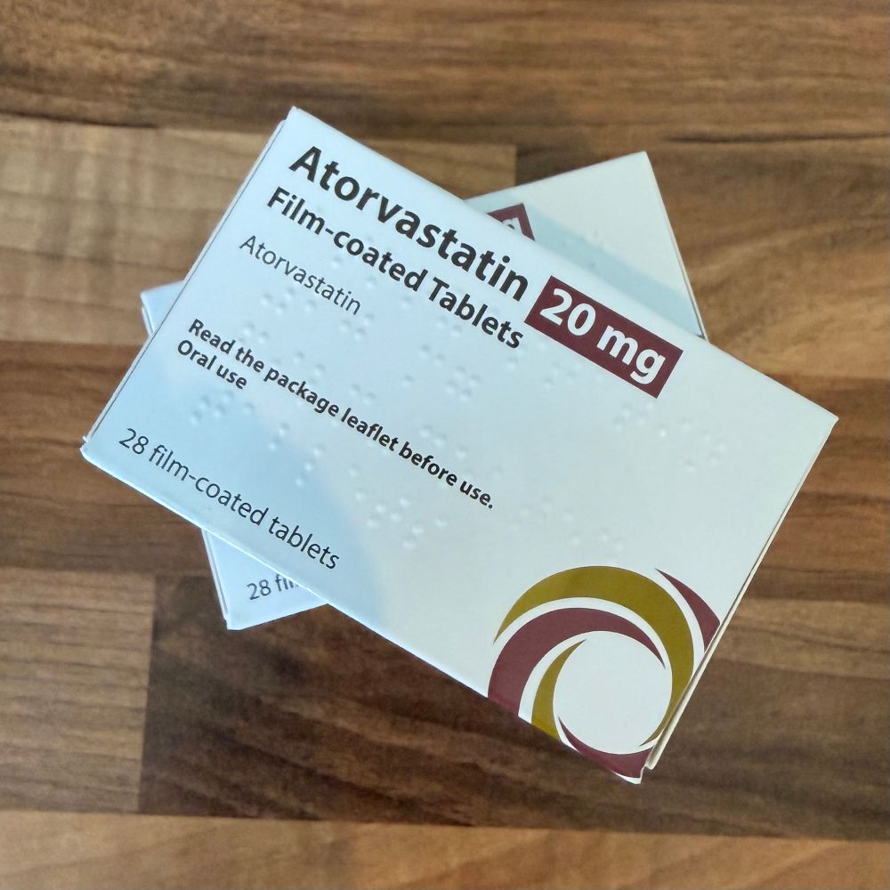 Two white boxes of statins sit on a wooden surface. 