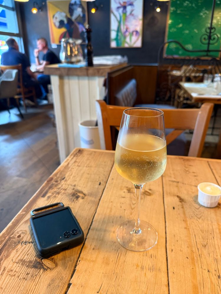 A glass of cold white wine sits on a wooden table. 