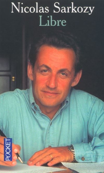 La couverture du livre de Sarkozy intitulée "libre". Elle montre une photo de lui en train de faire semblant d'écrire au stylo, regardant la caméra avec un petit sourire 