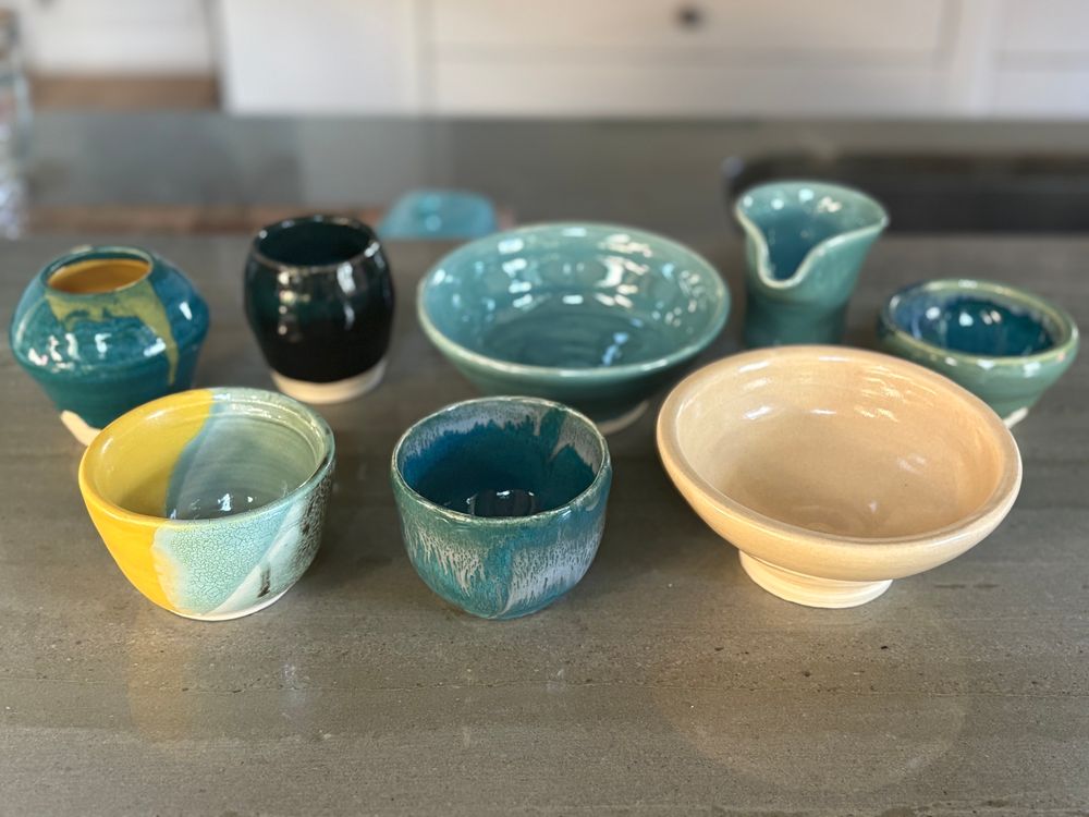 A collection of pottery bowls made by a beginning potter, in shades of yellow and teal
