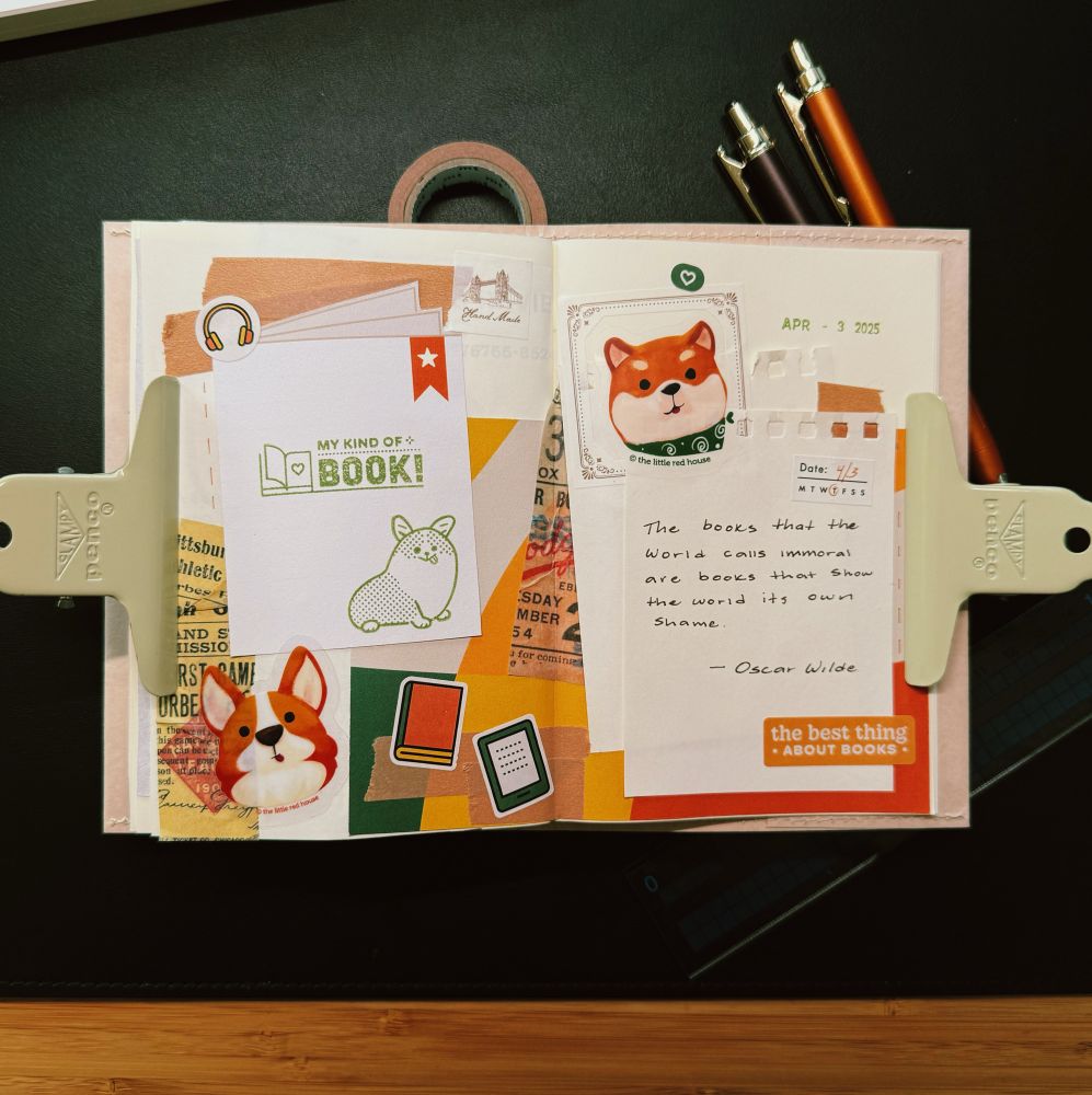A decorated journal spread with colorful paper scraps, stickers, and handwritten notes. The left page features a cut out of a book with the text “My kind of book!” and a cute corgi illustration, surrounded by various stickers including another corgi face, books, and vintage-style ticket stubs. The right page displays a quote by Oscar Wilde: “The books that the world calls immoral are books that show the world its own shame,” along with a Shiba Inu sticker and the date April 3, 2025. Two binder clips hold the pages open, and pens and washi tape rest at the top of the spread.