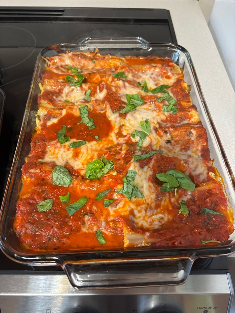 Noodle casserole topped with cheese & marinara, garnished with basil