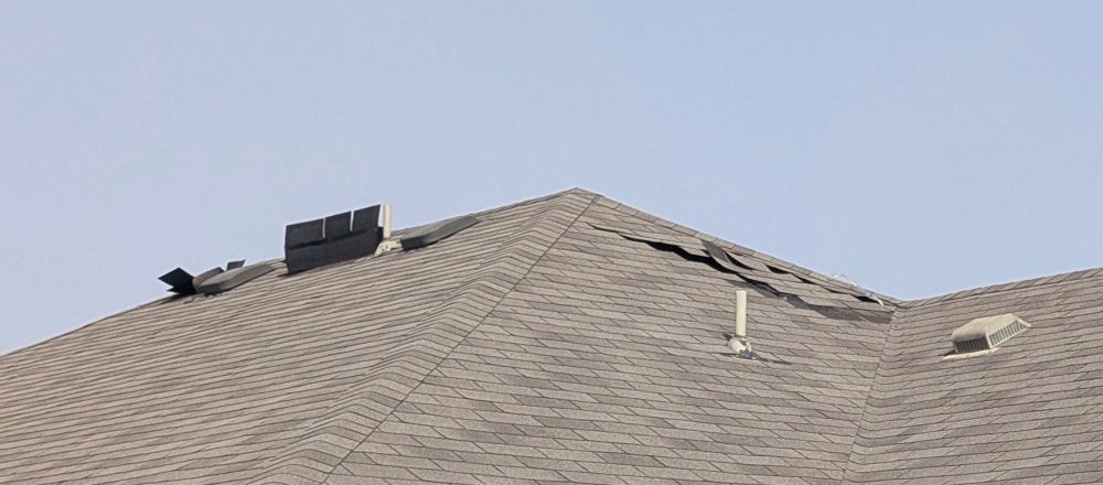 Photo of a roof in profile. Several of the roof shingles are sticking straight up in the air like a person who is riding a rollercoaster and sticks their hands into the air. "wheeeeee!" 