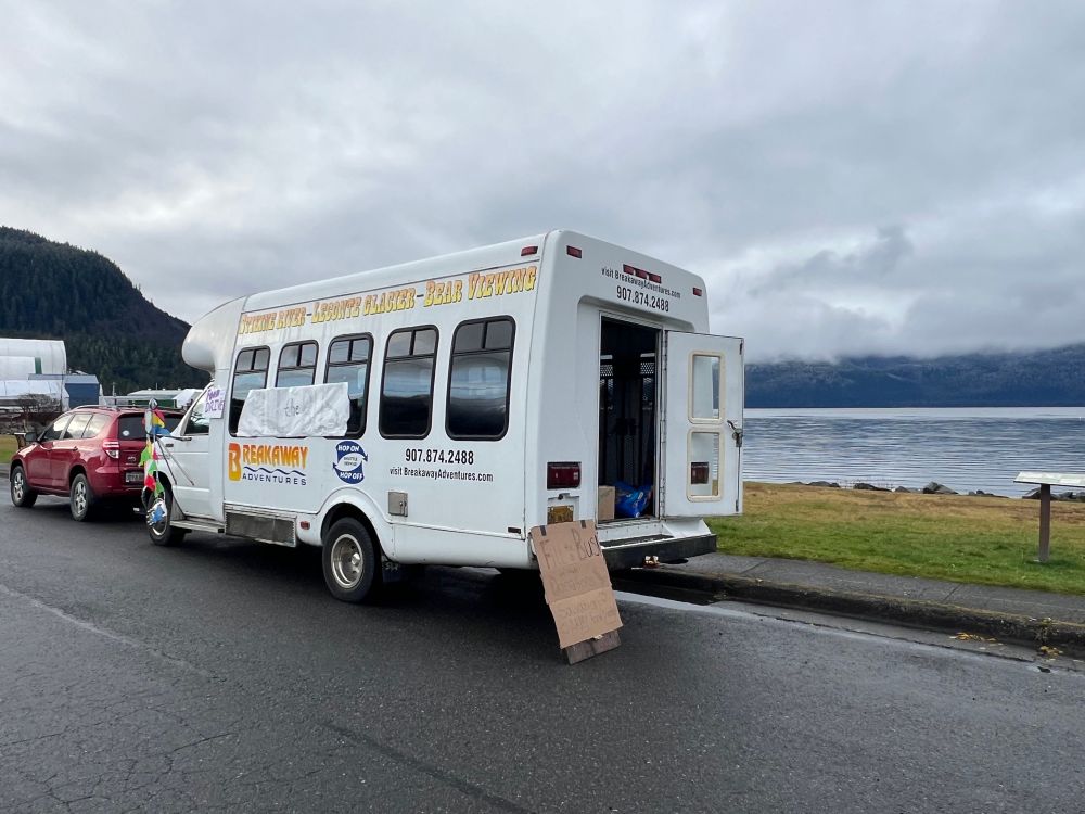 Airport bus sits beside ocean waiting for food donations. 