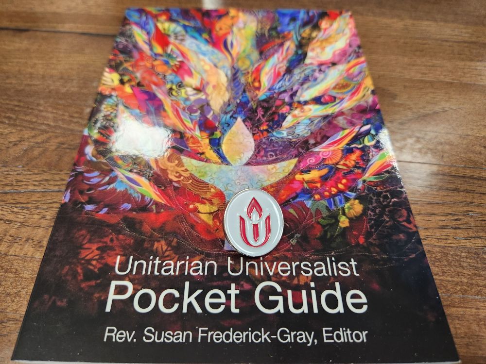 A picture of the Unitarian Universalist Pocket Guide edited by Rev. Susan Frederick-Gray with a UU chalice pin on top.