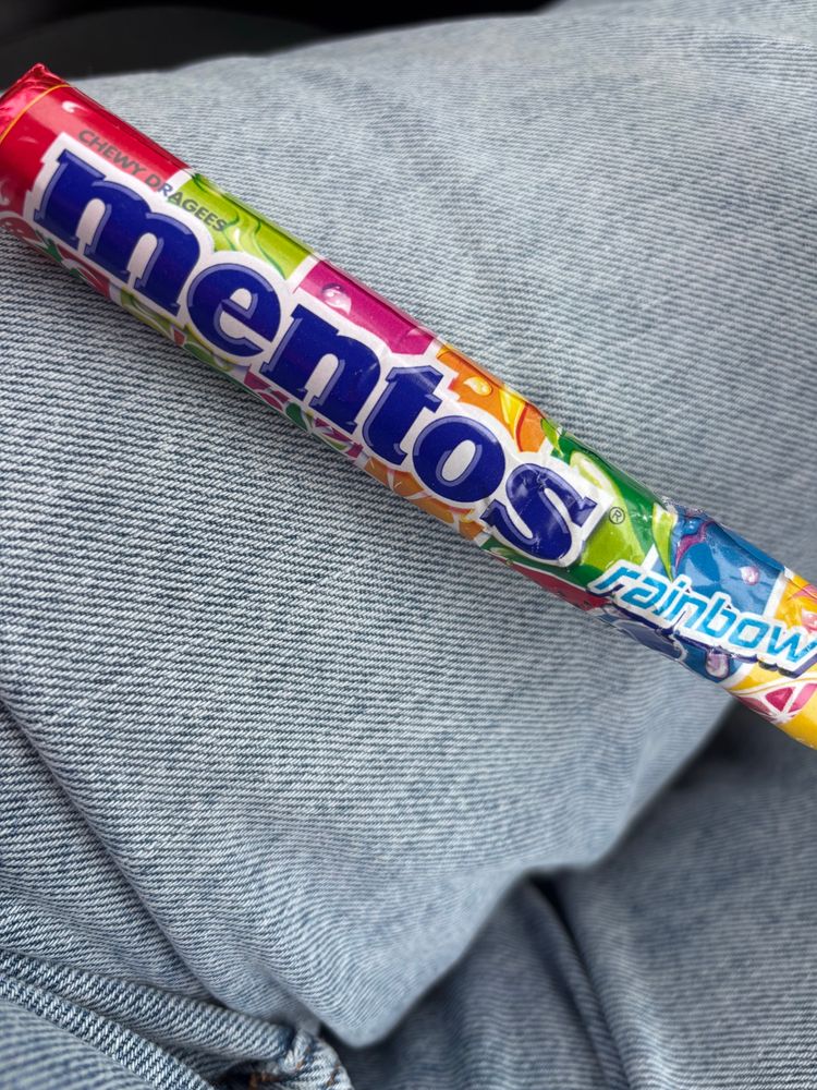 Photo of packet of fruit mentos sweets, sitting on my jeans clad leg.