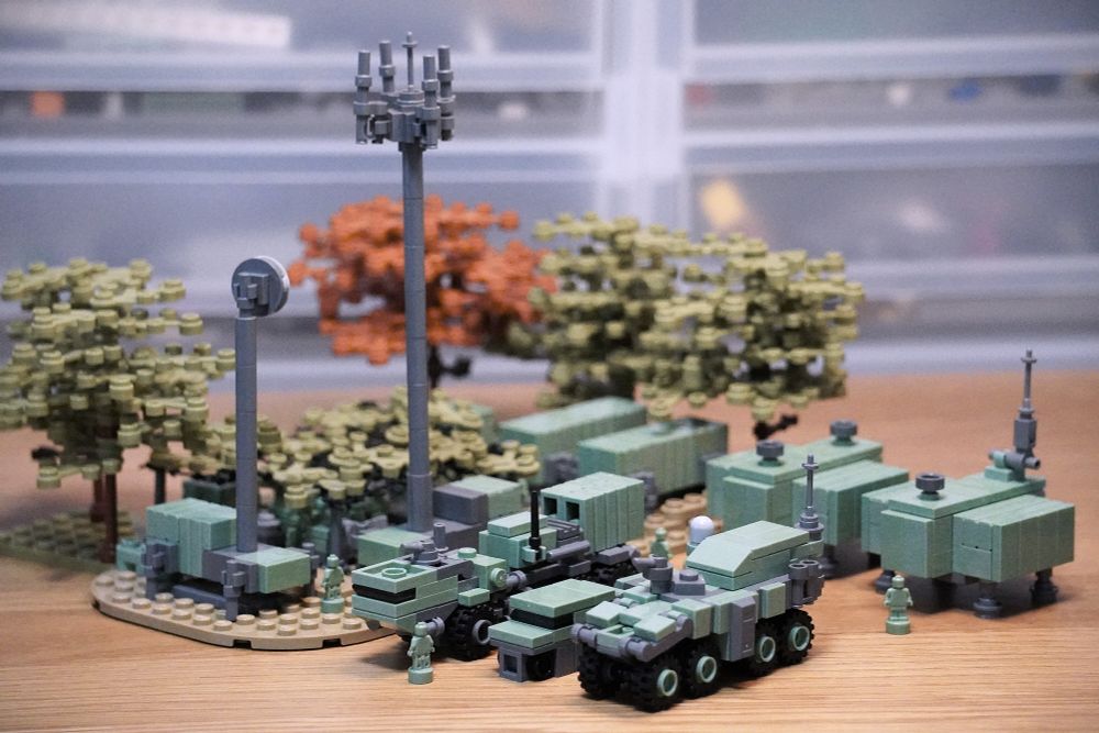 レゴブロックで作製された軍隊のキャンプです。林の中に装甲車やトラック、通信設備が並んでいます。