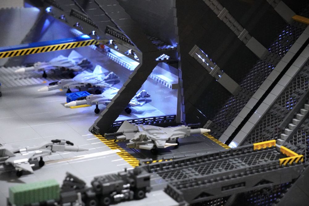 レゴブロックで作られた格納庫です。戦闘機が並んでおり、照明で照らされています。