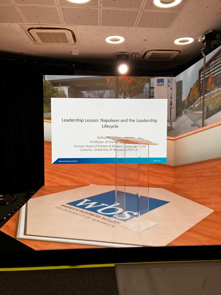 The business school smart stage set for my live lesson with the front slide of my PowerPoint and a photo of campus in autumn