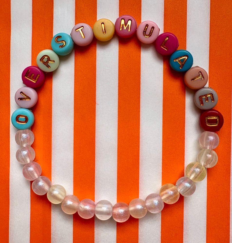 A bracelet reading OVERSTIMULATED