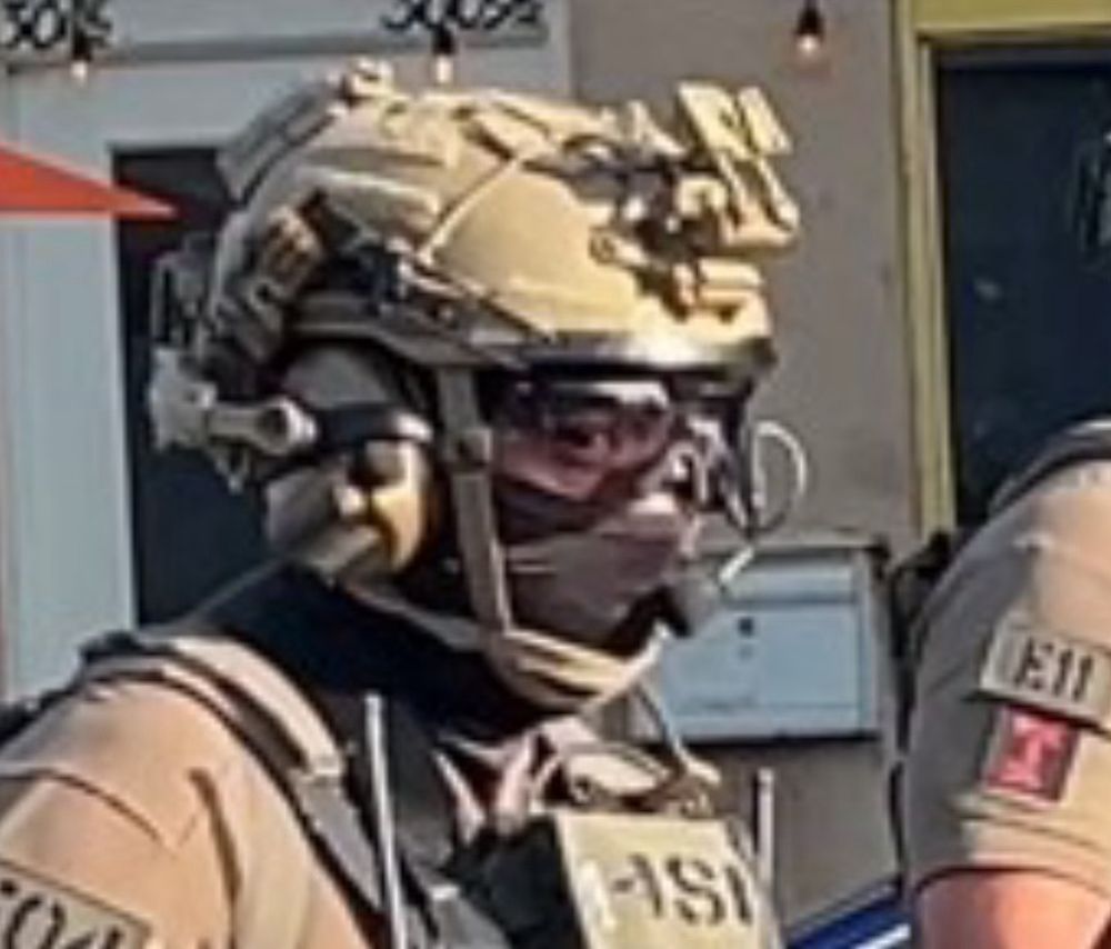 Closeup of cop in tactical cosplay looking like he’s not cool with the whole situation but needs the paycheck. 
