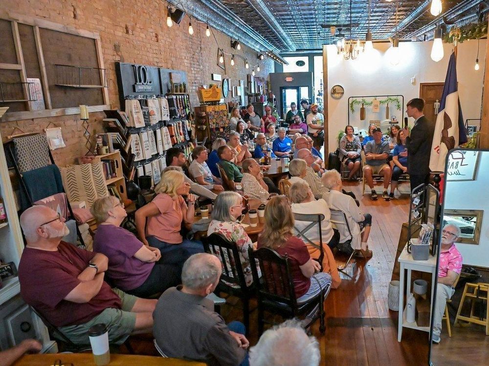 A photo of Rob Sand at a coffee shop speaking to a crowd of people during his Town Hall Tour. 
