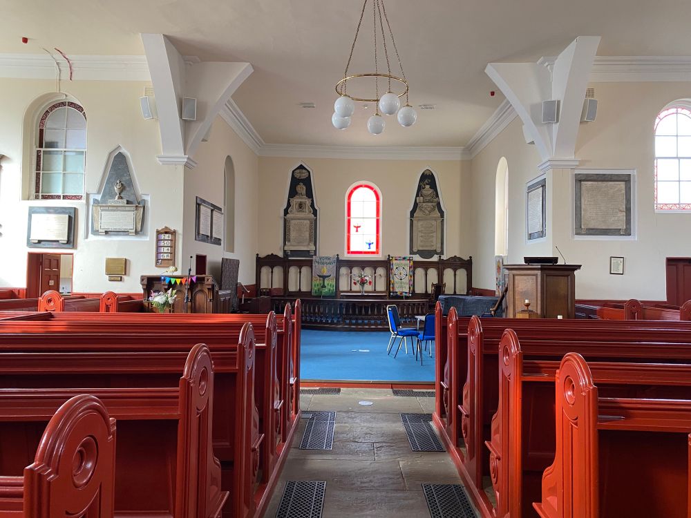 Interior of York Unitarian Chapel, with red pews and beautiful interior decor 
