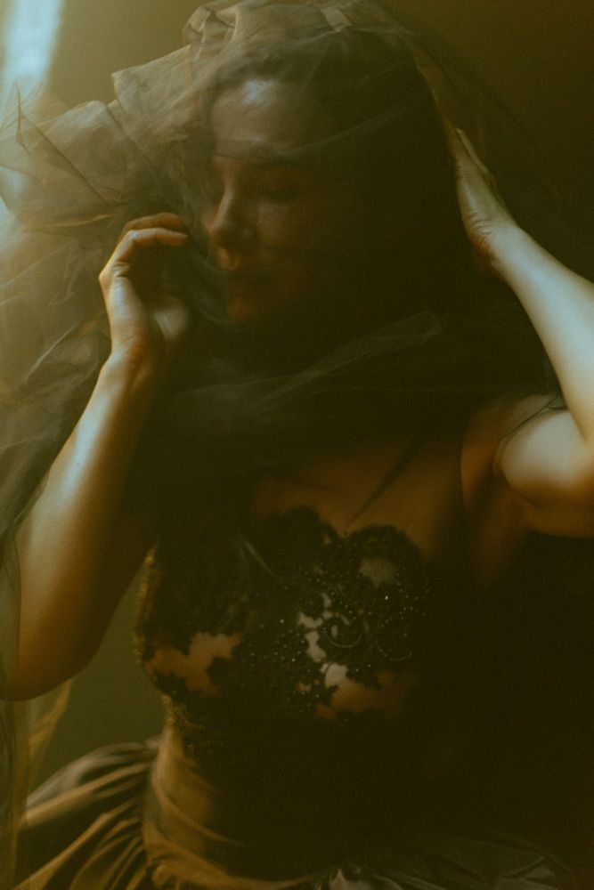 Film photograph by Heather Hazzan of Chella Ferrow in black lace and silk faille gown by Corvus Crux. Model wears impromptu veil of black tulle.