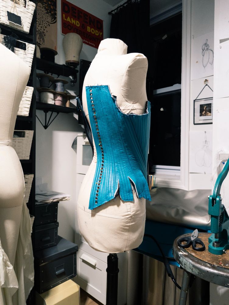 Nearly finished blue stays on a dress form seen from behind. 