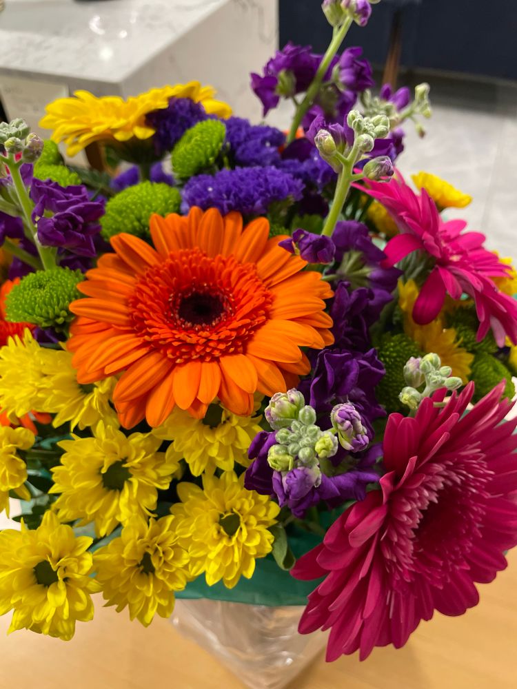 A bouquet of yellow, orange, purple, and pink flowers 