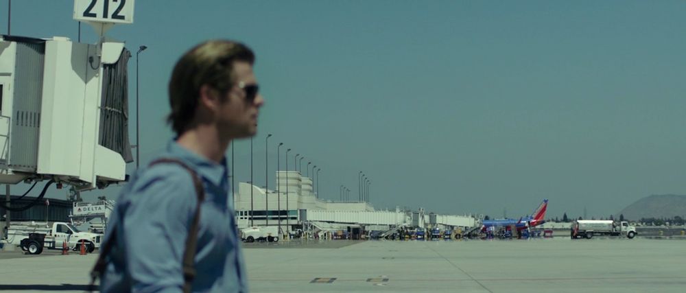 Chris Hemsworth as a blackhat hacker named Hathaway walking on the tarmac towards his plane in BLACKHAT (Michael Mann, 2015)