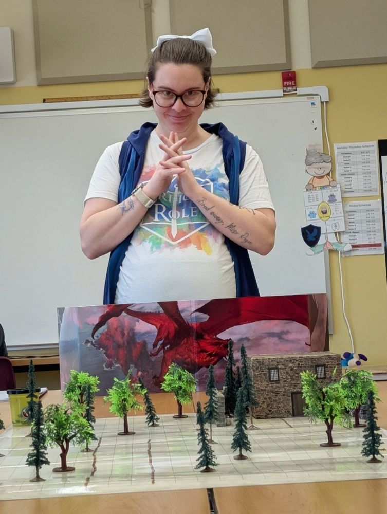 Shannon standing behind a Dungeon Master screen and a combat battle map