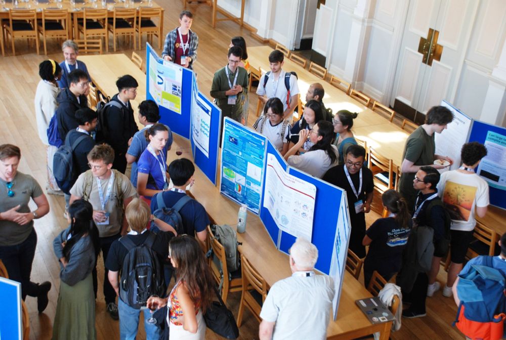 Attendees of ICCS's 2025 Summer School enjoy a poster session, with groups of people reading and discussing poster content