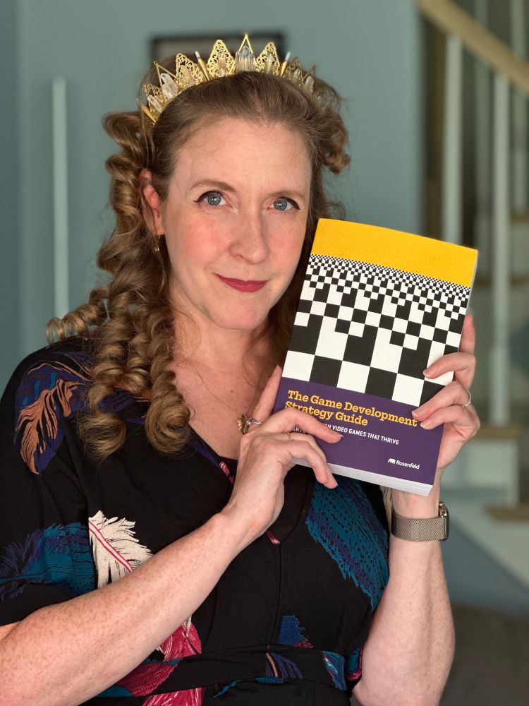 Cheryl Platz posing after unboxing her first copy of The Game Development Strategy Guide at home. 