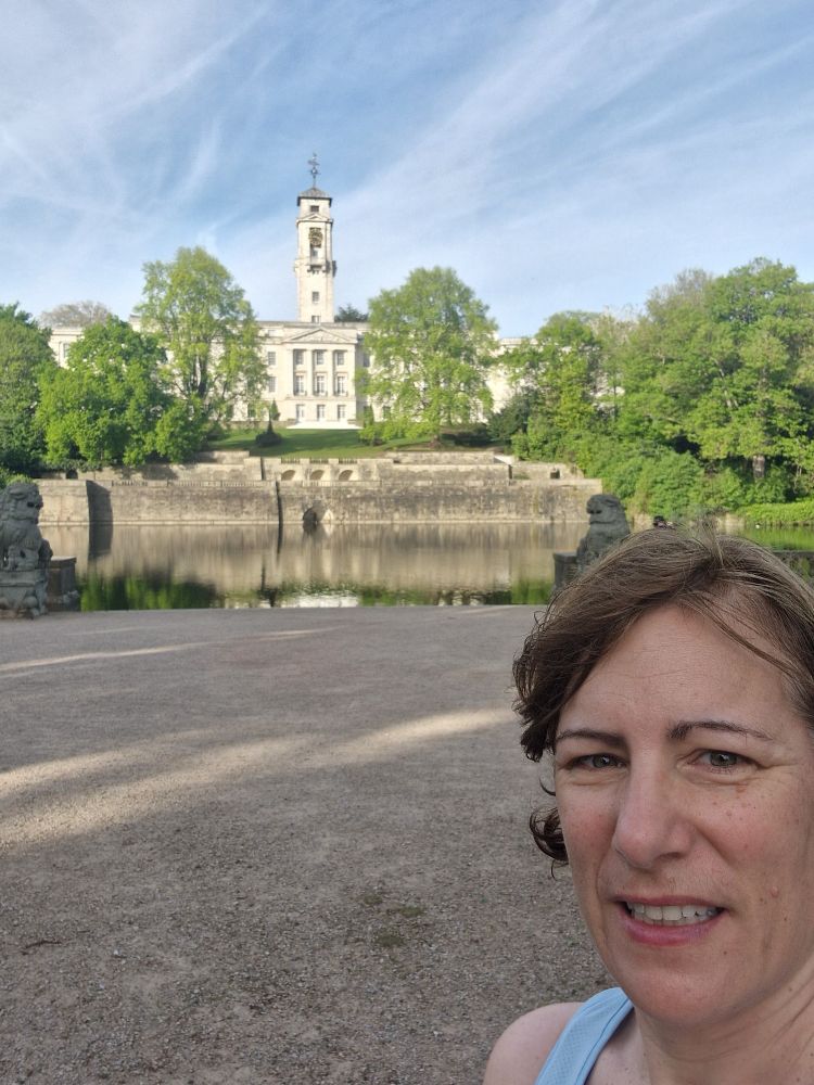 beutiful stone building with clo
ck in front of lake

