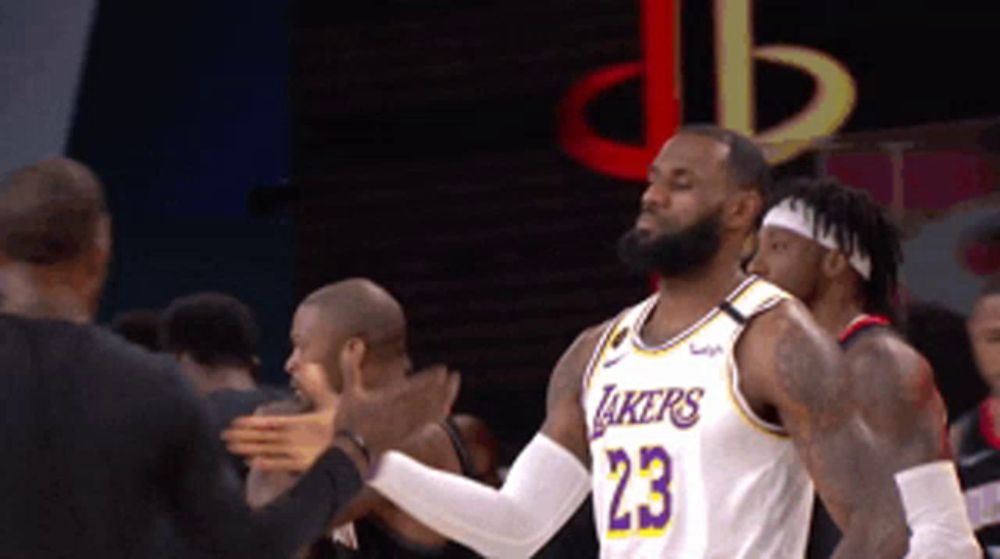 a basketball player wearing a lakers jersey is being congratulated by his teammates