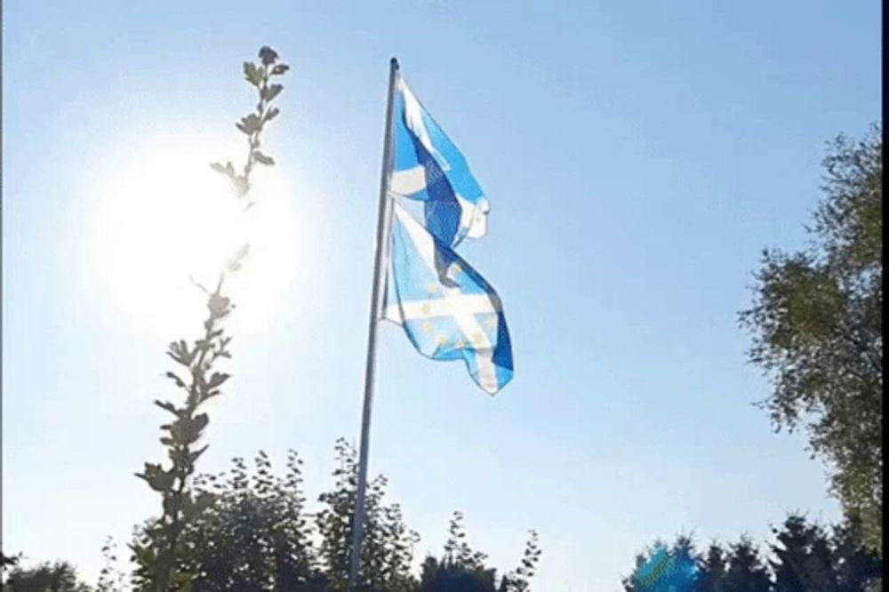 a blue and white flag is flying in the wind against a blue sky