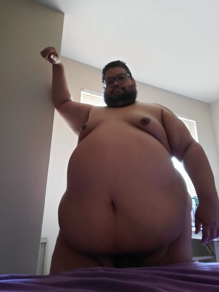 Big naked guy standing in front of window.