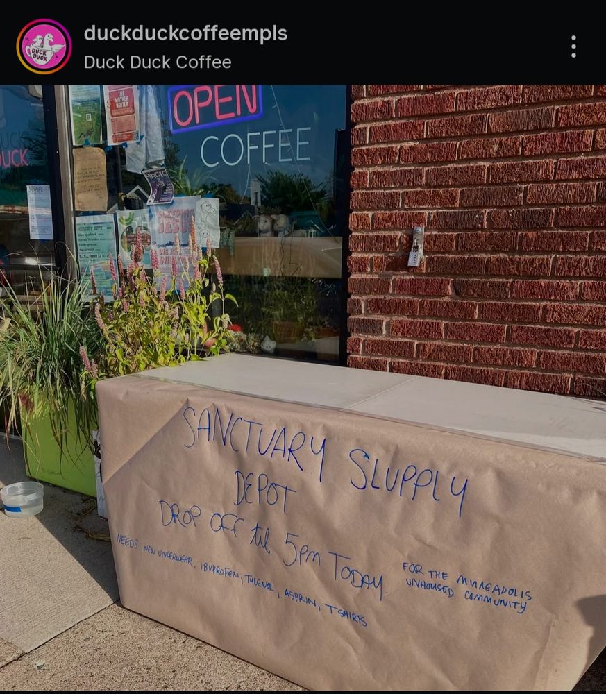 Screenshot from Duck Duck Coffee's Instagram showing a table outside the coffee shop with handwritten signs advertising the donation drive for Sanctuary Supply Depot.