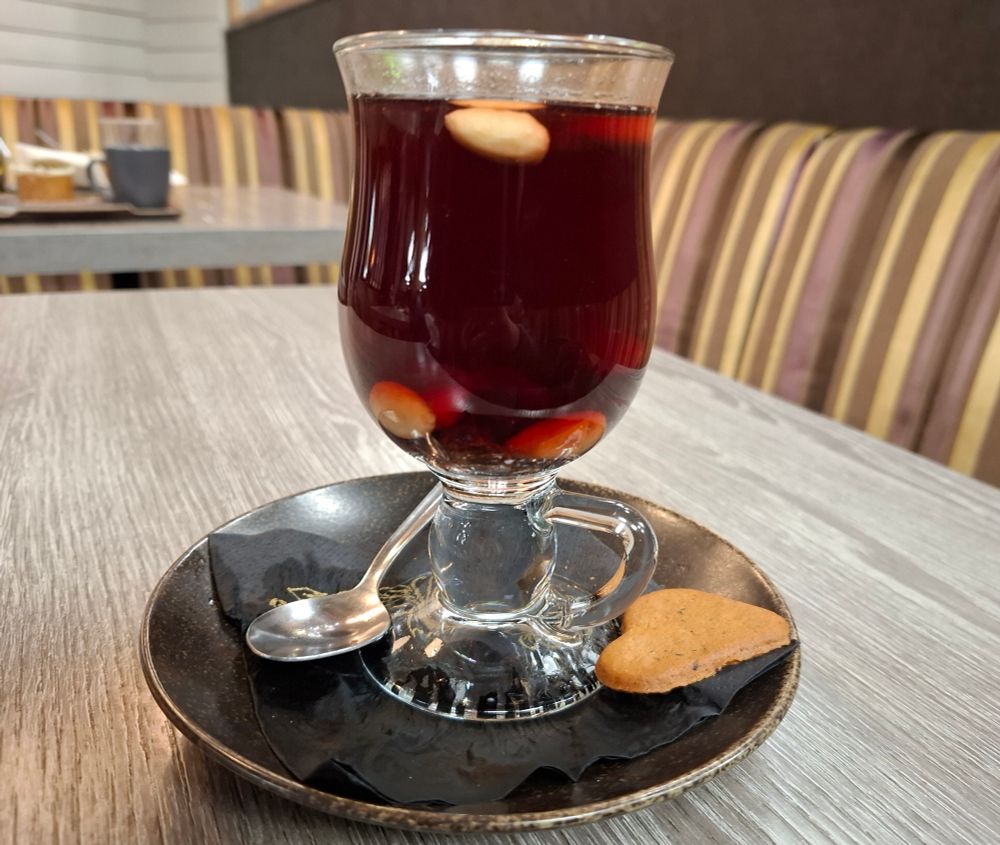 Glögi  jossa on mausteena manteleita ja rusinoita.Lautasella sydämenmuotoinen piparkakku.