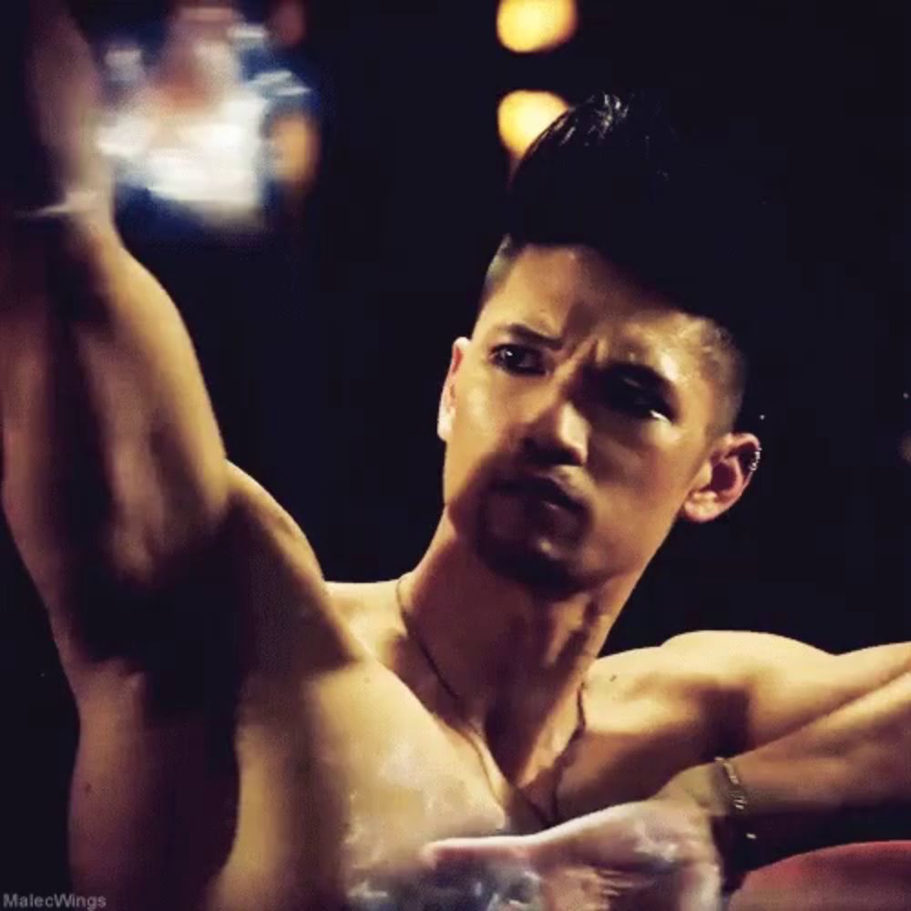 a shirtless man in a dark room with malecwings written below him