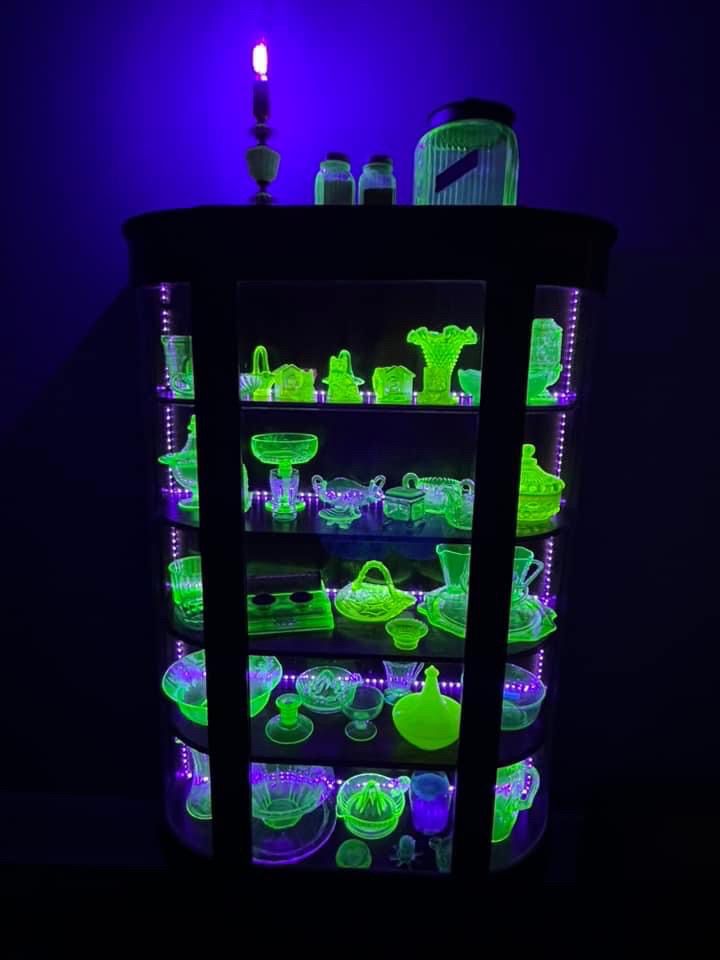 A cabinet of glowing glass. Glasses, vases, pitchers and bowls - all in a fluorescent green.