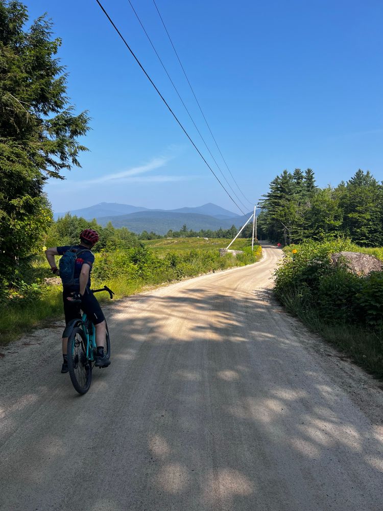 Man stopped on a gravel bike stopped to admire the view into the New Hampshire mountains
