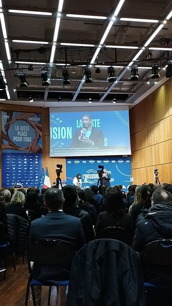 Foule assise devant Saïd Hammouche, sur scène, parlant dans un micro.