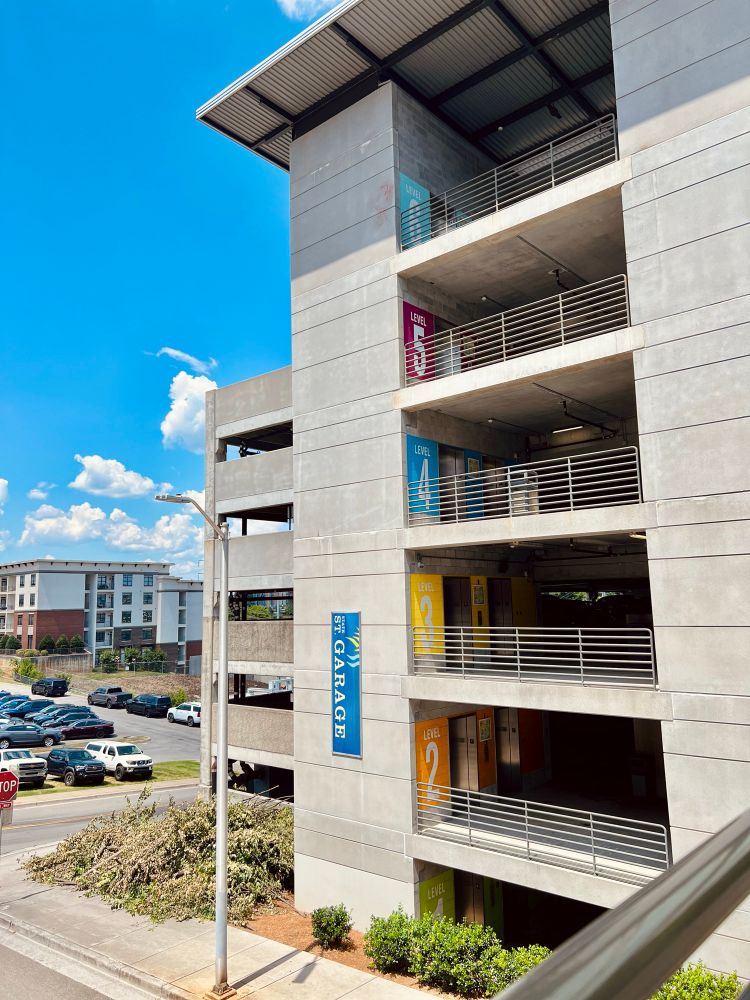 A downtown city garage with colorful floor signage, against a blue sky with white clouds 