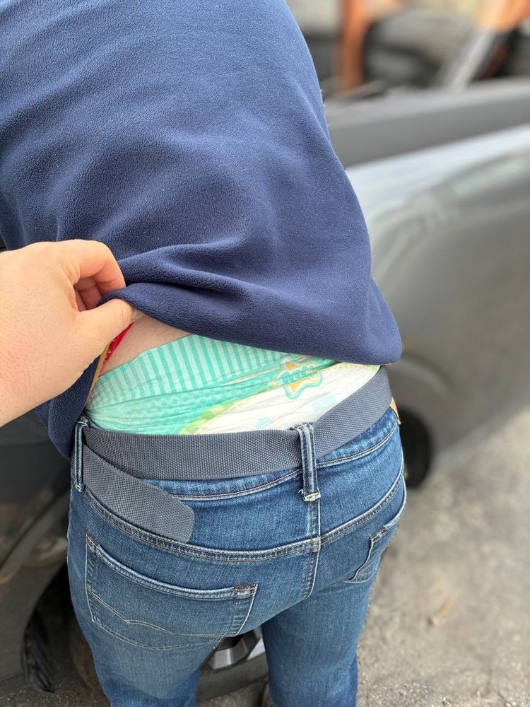 A diaper waistband peeking out from underneath a boy’s jeans