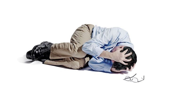 Person lying on the floor in the fetal position holding their head