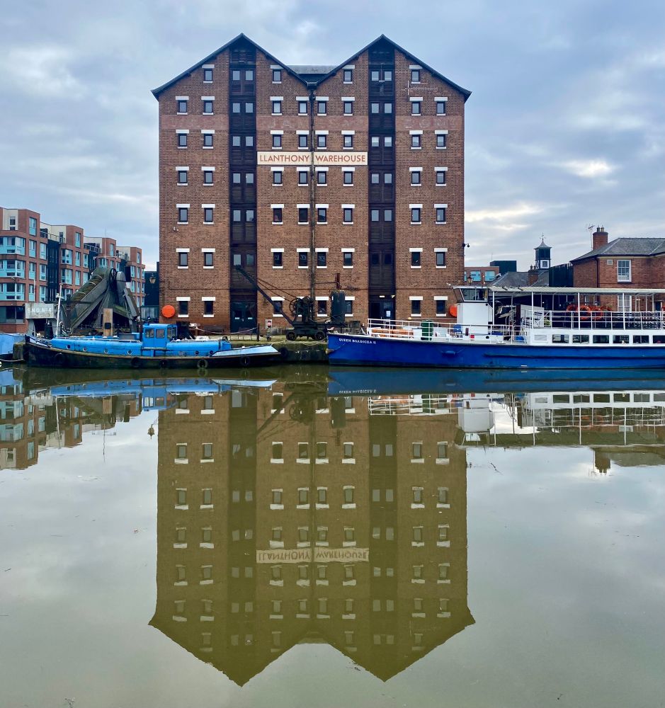 Seven-storey brick-built Victorian warehouse by the dockside. Painted sign saying LLANTHONY WAREHOUSE. 