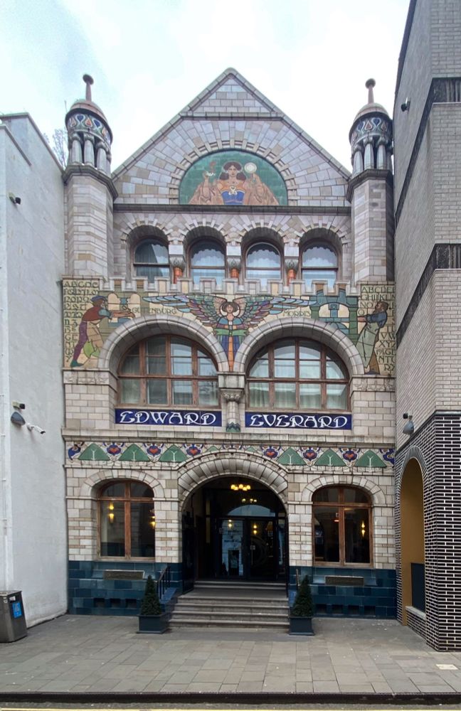Coloured tile-clad frontage with images of Johannes Gutenberg, William Morris, an angelic figure holding a book, etc. 