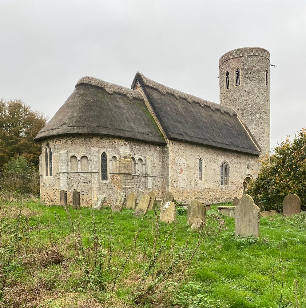 Norman church with thatched roof and round tower. 