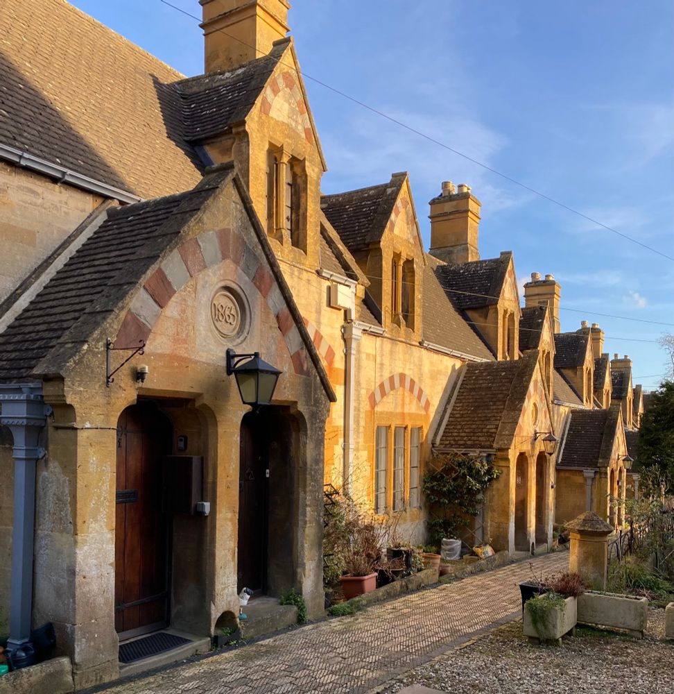 Row of small houses in Cotswold stone with polychrome stone arches. 