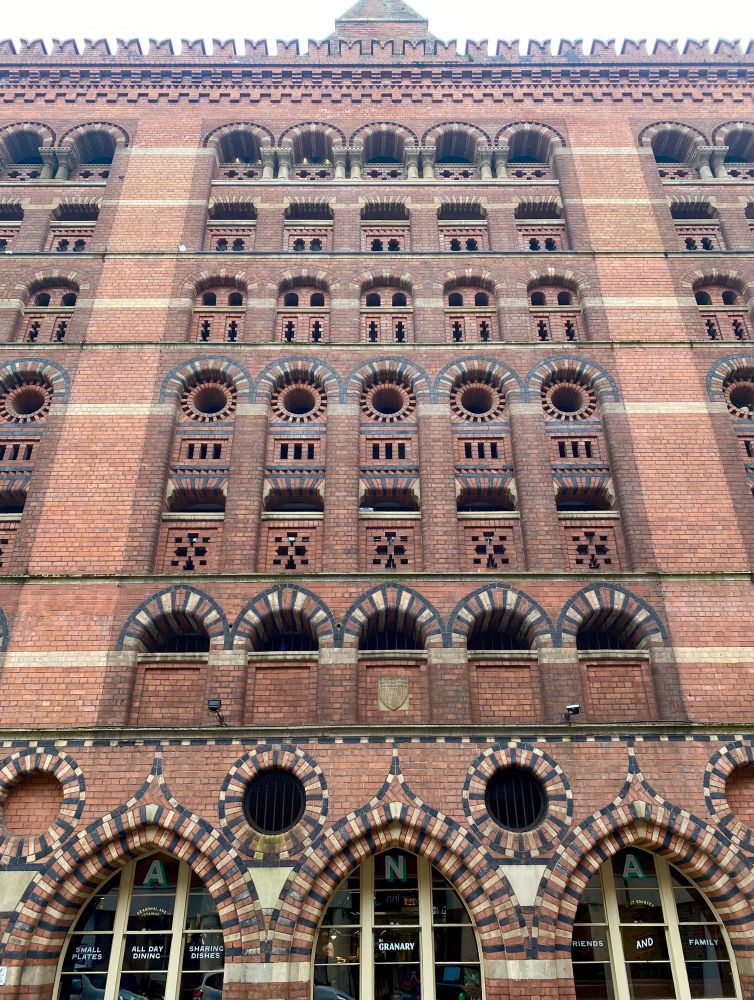 Flank wall of multi-storey Victorian granary building. Polychrome brickwork in red, black and buff with round-arched, pointed, circular and slit-shaped openings. 
