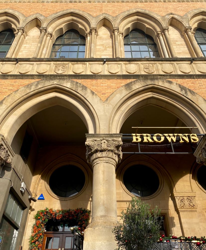 Pointed Gothic arches and carved capitals on the open arcade that fronts this stone and brick building. 